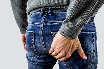 Man holding buttocks in pain wearing jeans and sweater