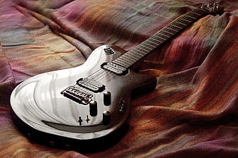 Silver electric guitar on colorful striped fabric background