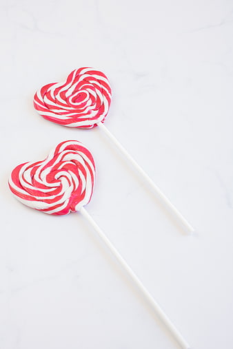 Two Heart-Shaped Pink and White Swirl Lollipops on White Marble
