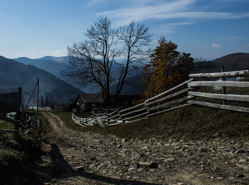 Rural Mountain Landscape with Wooden Fence and Autumn Trees