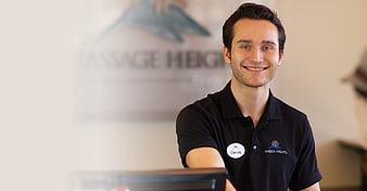 Smiling male receptionist in black polo shirt at spa front desk