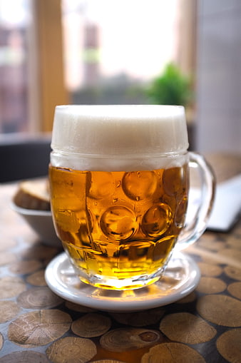 Cold glass of golden beer with foam on wooden table