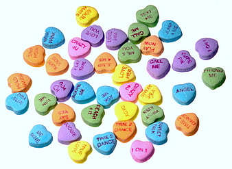 Scattered colorful conversation hearts candy on white background