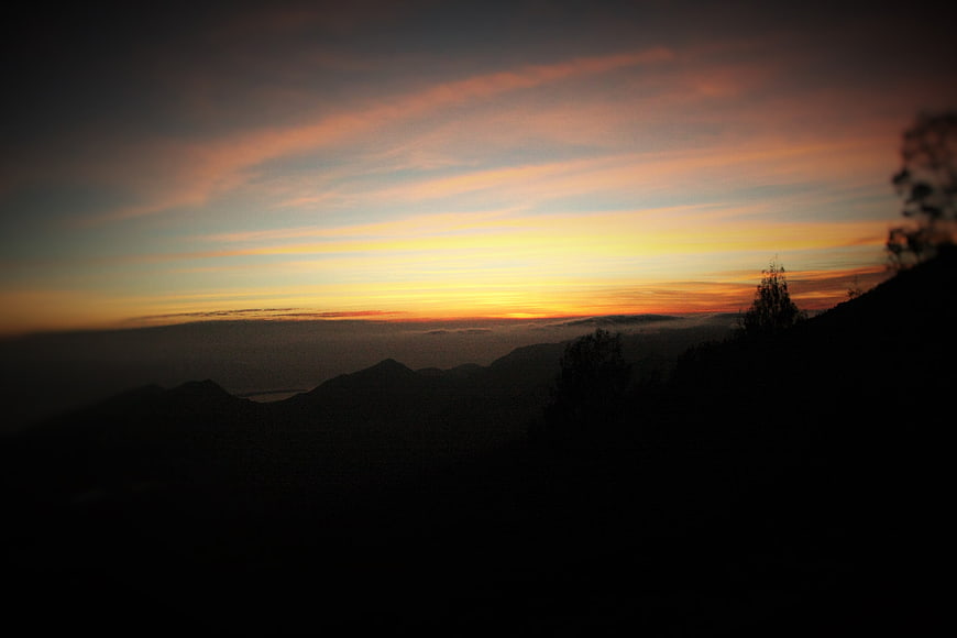 Dramatic sunset over silhouetted mountain range with orange sky