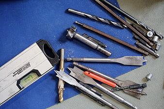 Assorted drill bits and level on blue work surface