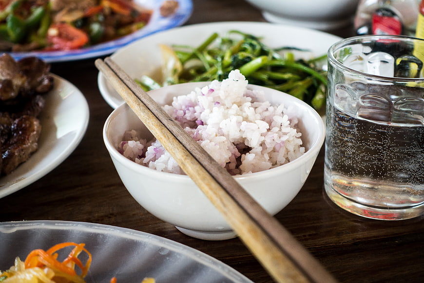 Bowl of rice with chopsticks and side dishes