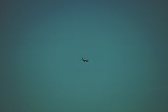Silhouette of Airplane Flying in Teal Sky