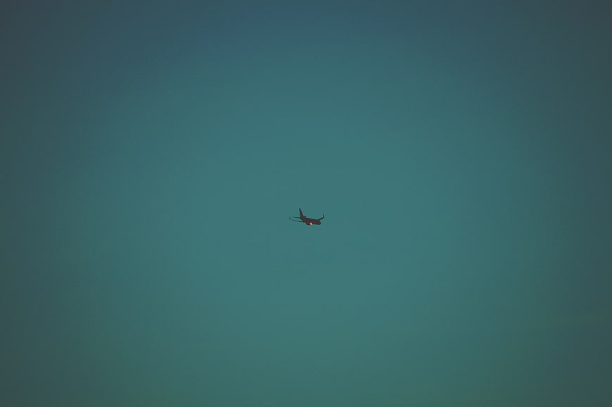 Silhouette of Airplane Flying in Teal Sky