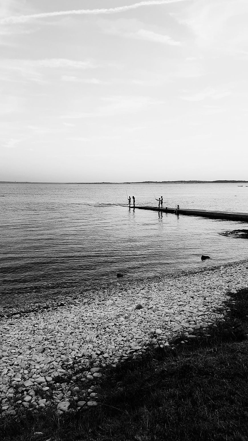 Black and white photo of people fishing on a pier
