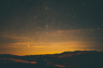 Starry Night Sky Over Mountain Landscape with Golden Horizon