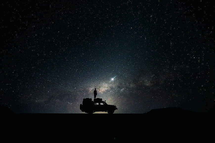 Silhouette of Man Standing on Car Under Milky Way