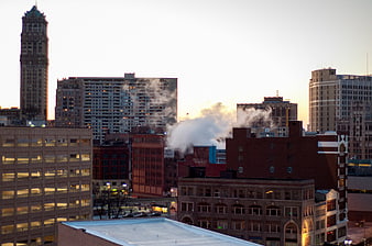 Urban City Skyline with Steam Rising at Sunset
