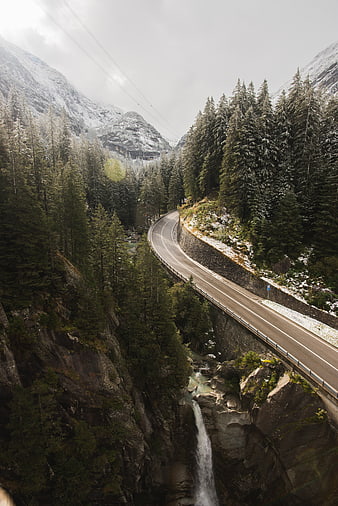 Winding Mountain Road Through Snowy Forest with Waterfall