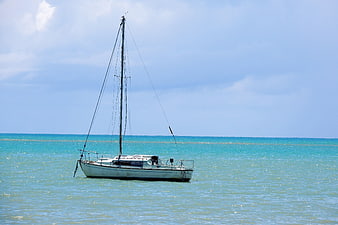 White sailboat anchored in turquoise ocean water