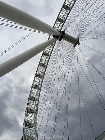Low angle view of London Eye ferris wheel against cloudy sky
