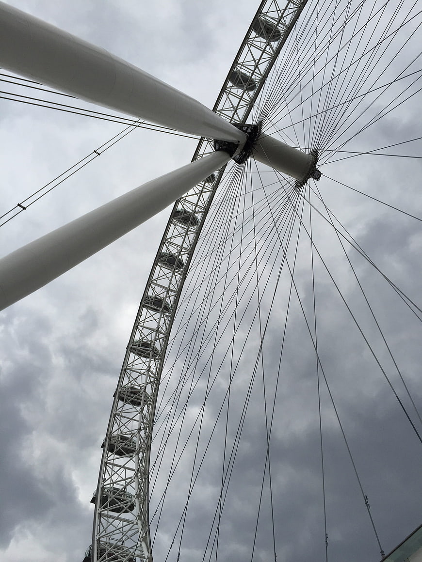 Low angle view of London Eye ferris wheel against cloudy sky