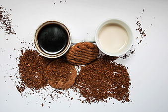 Top view of black coffee, milk, and chocolate cookies with cocoa nibs