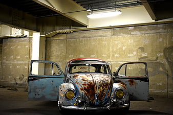 Rusty vintage Volkswagen Beetle with open doors in garage