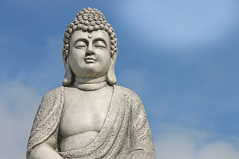 Stone Buddha statue close-up against blue sky