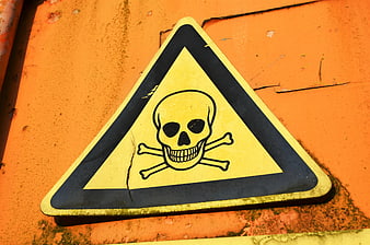 Weathered Yellow Skull And Crossbones Warning Sign On Orange Metal Surface