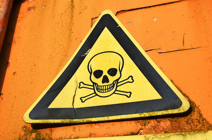 Weathered Yellow Skull And Crossbones Warning Sign On Orange Metal Surface
