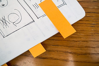 Hand-drawn wireframe sketches with sticky notes on wooden desk