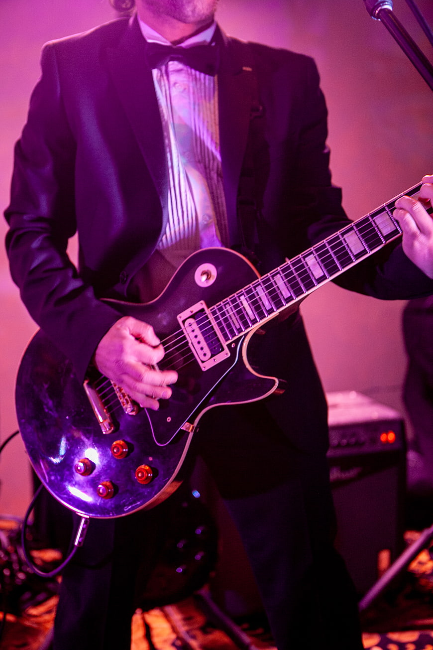 Musician playing electric guitar on stage in tuxedo