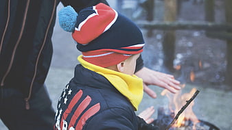 Child warming hands by outdoor fire in winter