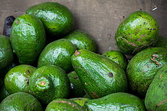 Fresh green avocados in a wooden crate