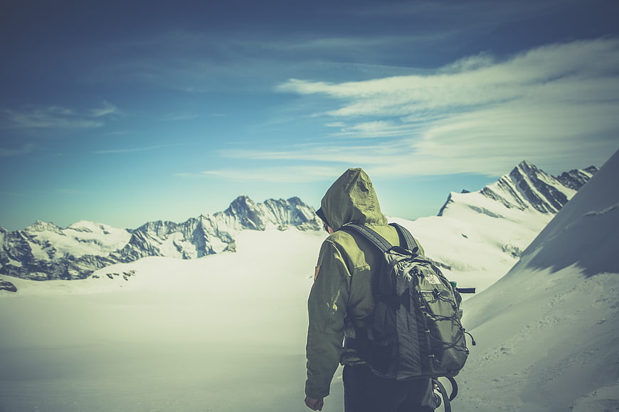Hiker with Backpack Looking at Snowy Mountain Peaks