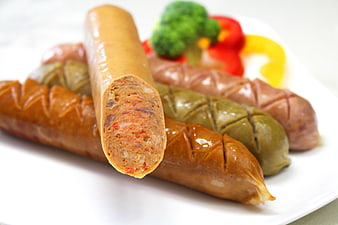 Assorted cooked sausages with vegetable garnish on white plate