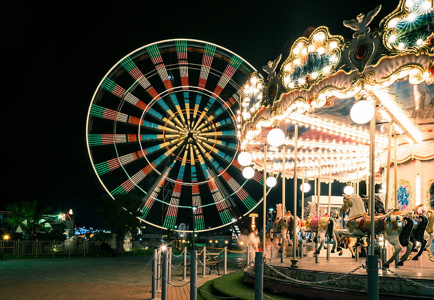 Illuminated Ferris Wheel and Carousel at Night in Amusement Park