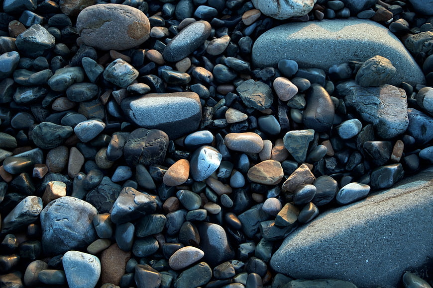 Close-up of smooth gray and blue river stones on a beach