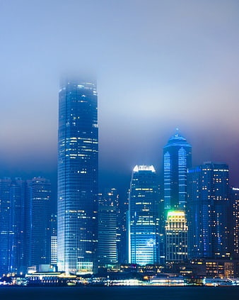 Foggy Hong Kong skyline at night with illuminated skyscrapers