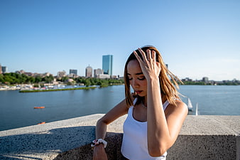 Young woman looking down by river with city skyline