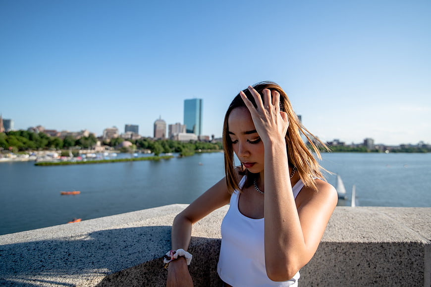 Young woman looking down by river with city skyline