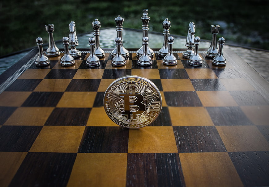 Bitcoin coin on chessboard with silver pieces