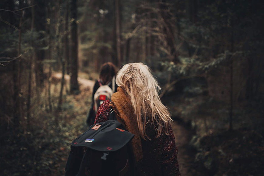 Two Women Hiking Through Dark Forest Trail