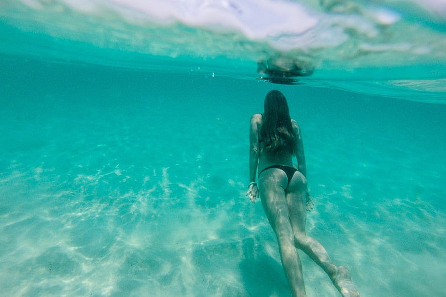 Woman Swimming Underwater in Turquoise Ocean