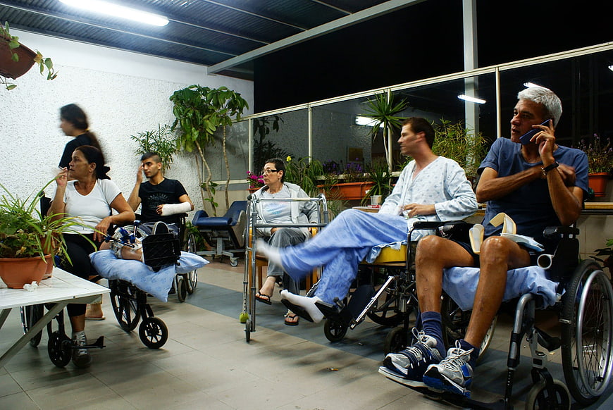Patients in wheelchairs waiting in hospital corridor at night