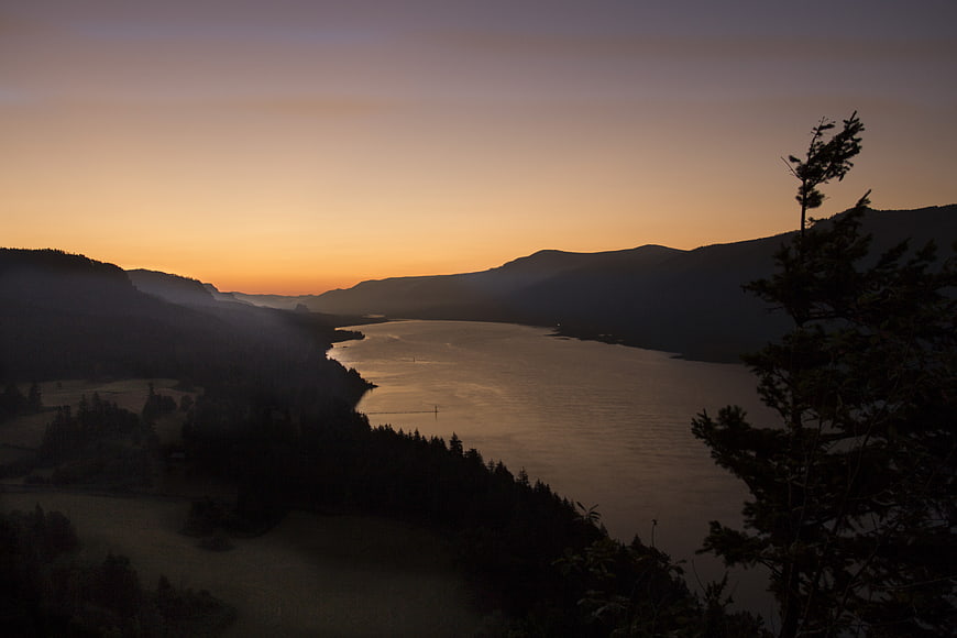 Serene Lake at Dusk with Silhouetted Mountains and Mist