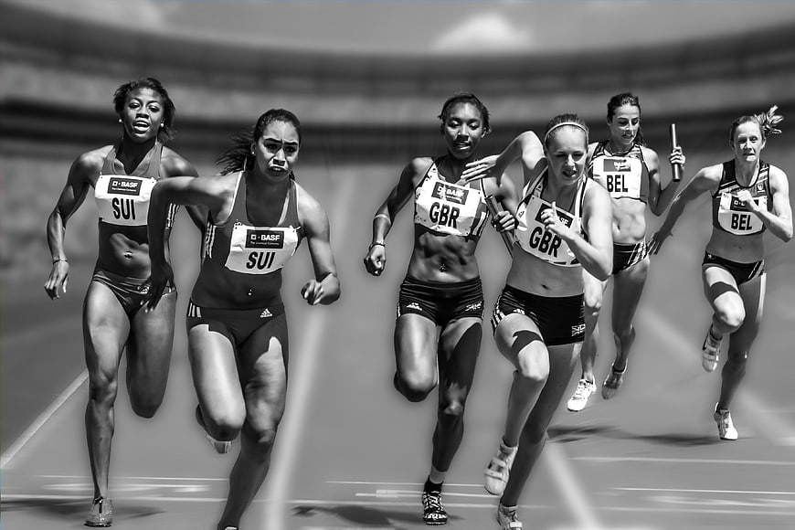 Female Athletes Sprinting in Track Relay Race