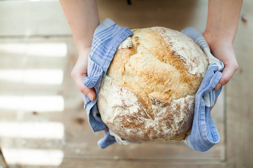 Hands holding fresh artisan sourdough bread loaf