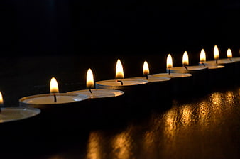 Row of Lit Tea Light Candles in Dark Setting
