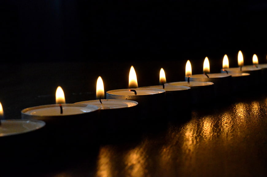 Row of Lit Tea Light Candles in Dark Setting