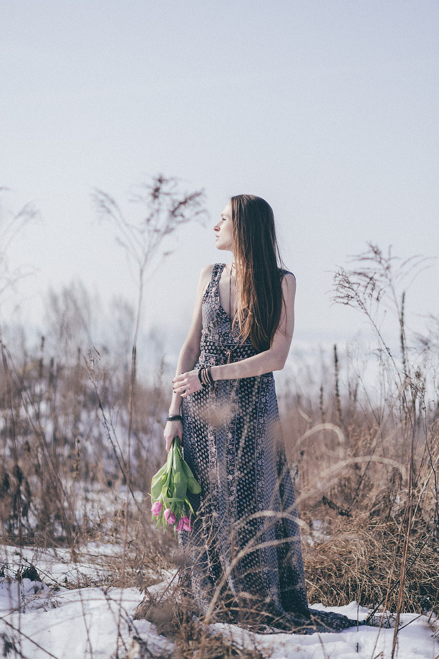 Woman in Patterned Dress Holding Pink Tulips in Snowy Field