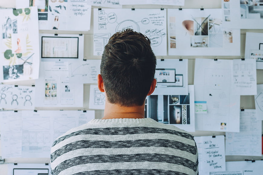 Designer Reviewing UX Wireframes and Mood Board on Office Wall