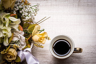 Top-Down View of Coffee Cup and Floral Bouquet on White Wood