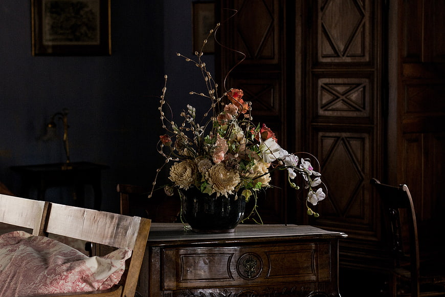 Vintage floral arrangement in dark moody interior with antique furniture