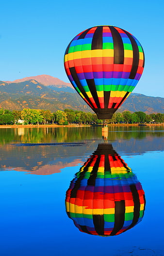Colorful Hot Air Balloon Reflection In Calm Lake With Mountain Background